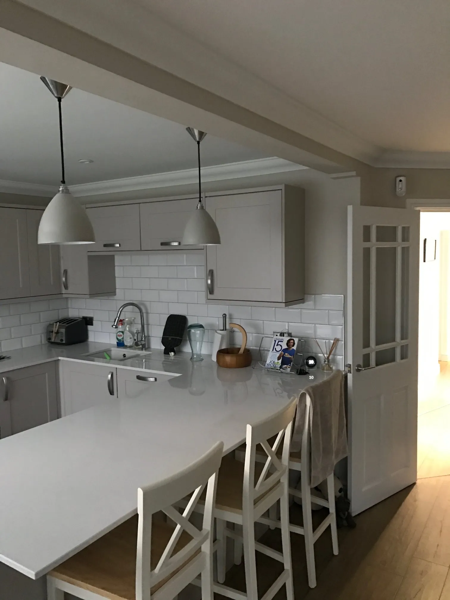 A kitchen with a white counter top next to a wooden floor.